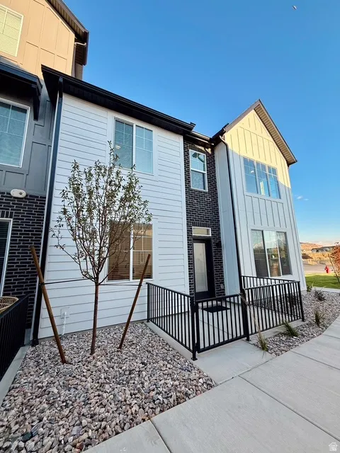 Modern townhome exterior featuring white horizontal siding and dark brick accents