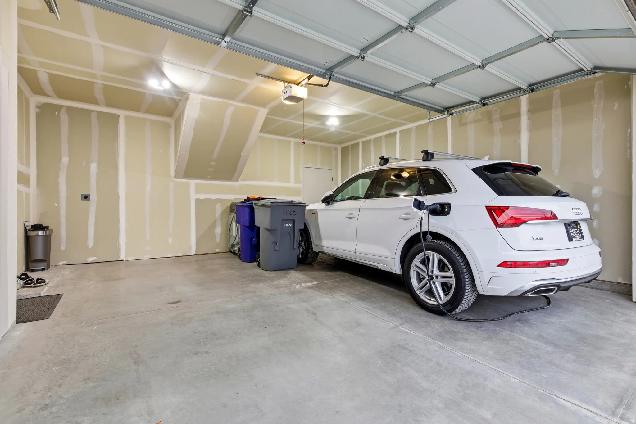 Spacious two-car garage featuring a concrete floor, an overhead garage door, and ample overhead lighting