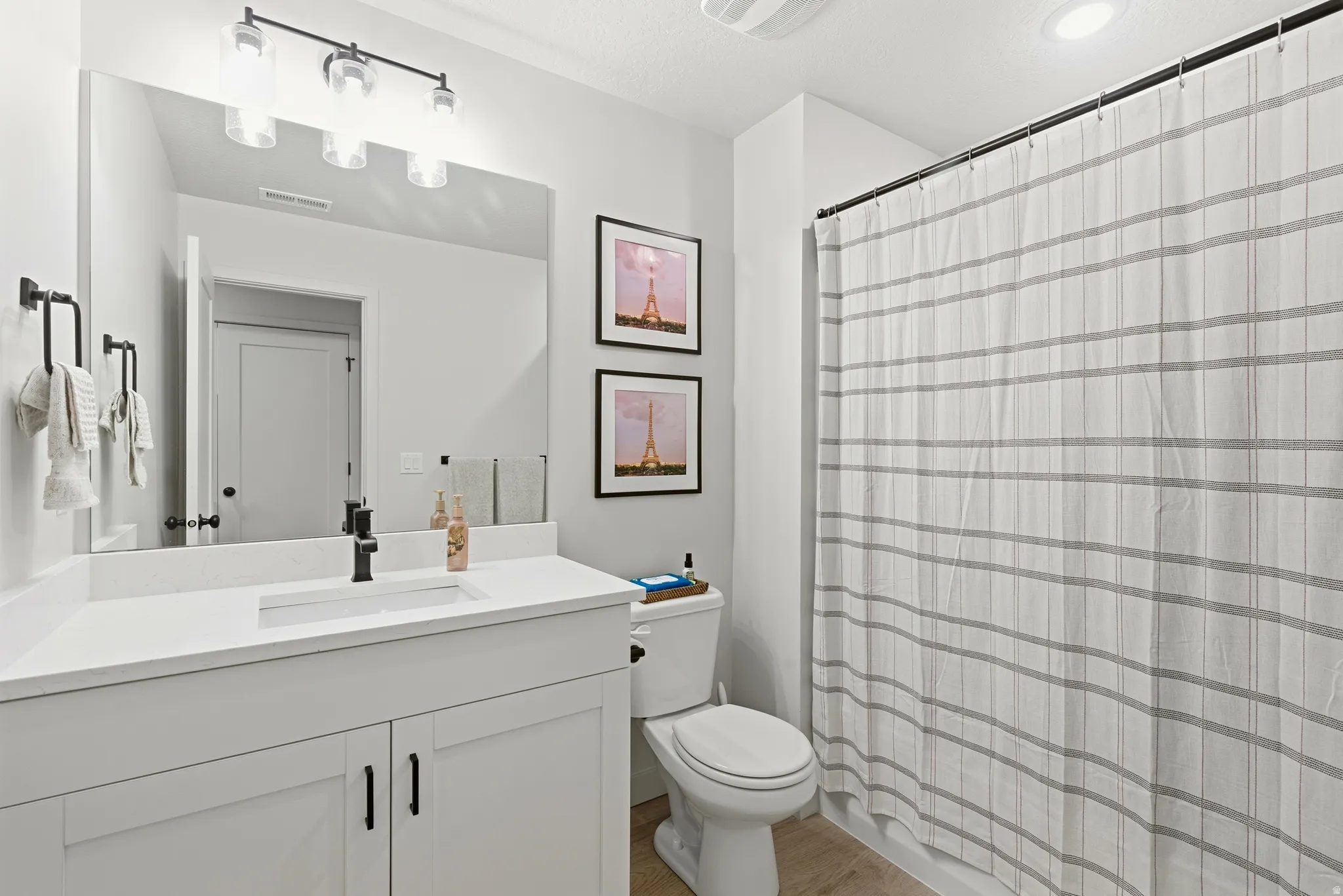 Bathroom featuring a white vanity with a rectangular undermount sink, a quartz-finish countertop, and matte black fixtures