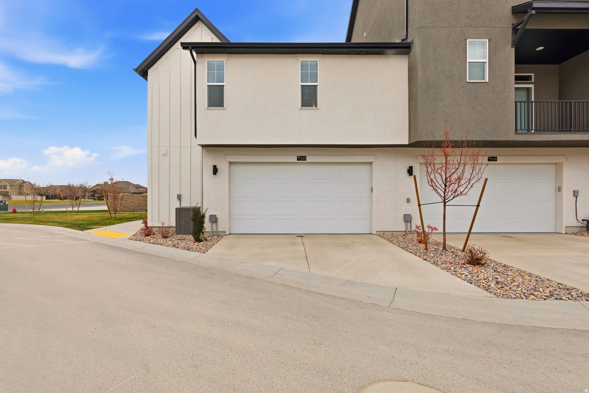 Contemporary exterior featuring white board and batten siding, stucco finishes, two private garage doors, and concrete driveways