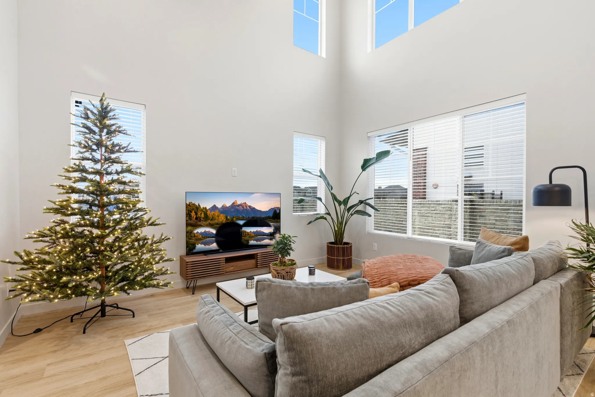 Living area featuring high ceilings, wood-finish flooring, and multiple windows
