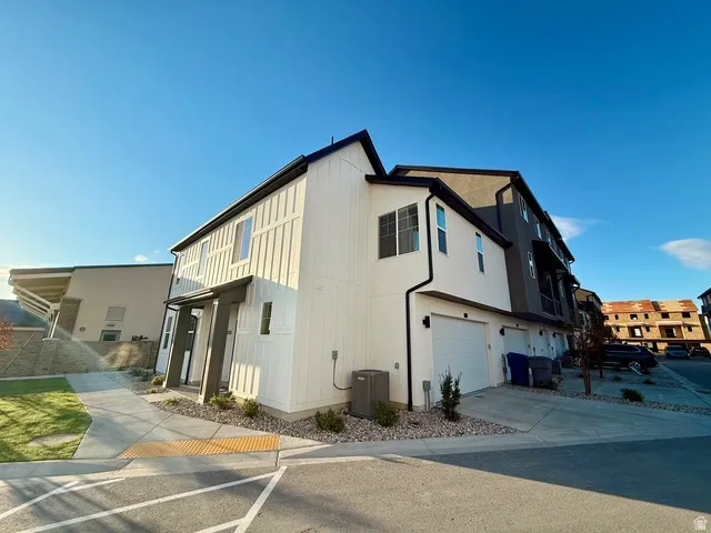 Contemporary townhouse exterior featuring a white vertical board and batten facade and dark trim accents