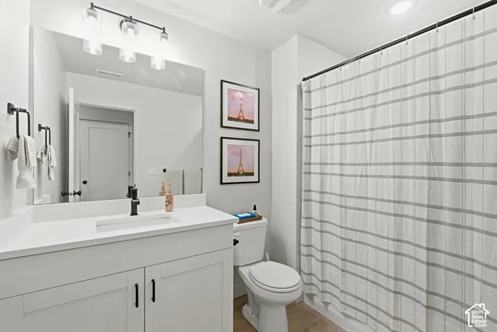 Bathroom featuring a white vanity with a rectangular undermount sink, a quartz-finish countertop, and matte black fixtures