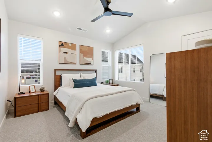 Bedroom featuring vaulted ceilings, recessed lighting, ceiling fan, carpet flooring, and multiple windows with blinds