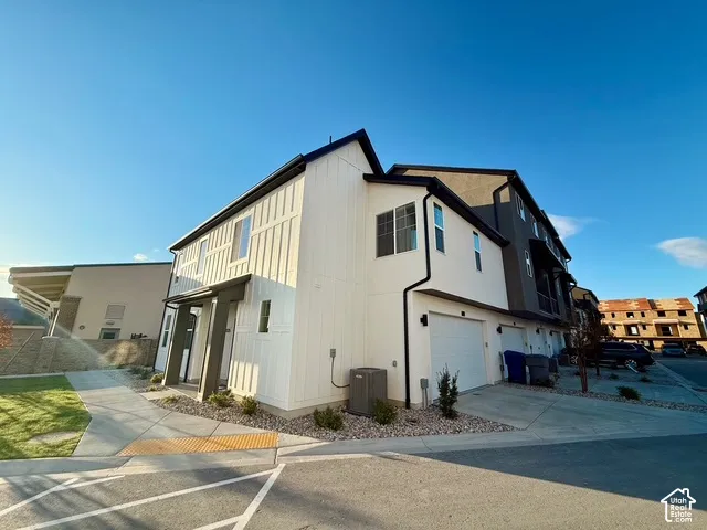 Contemporary townhouse exterior featuring a white vertical board and batten facade and dark trim accents