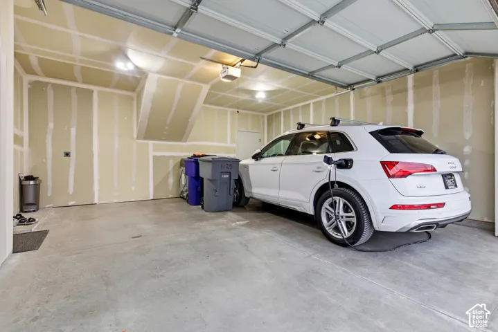 Spacious two-car garage featuring a concrete floor, an overhead garage door, and ample overhead lighting