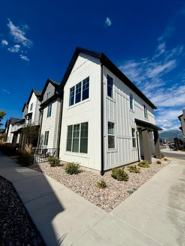 Two-story exterior with white board and batten siding, black framed windows, and a black gable roof