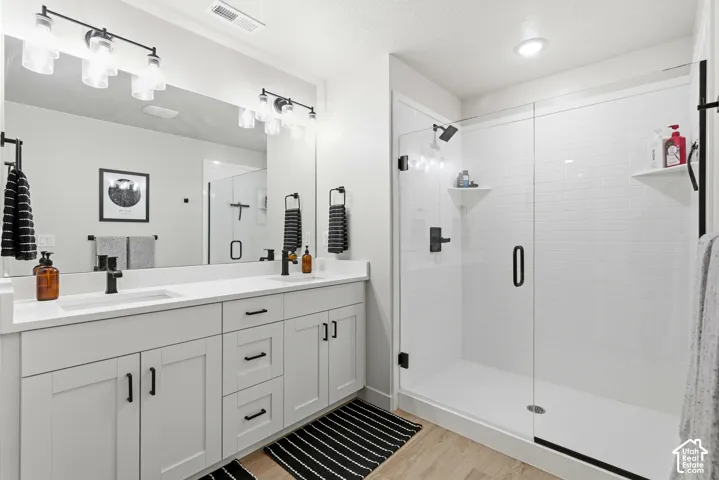 Modern bathroom featuring a dual vanity with white shaker-style cabinetry, quartz countertops, and matte black hardware