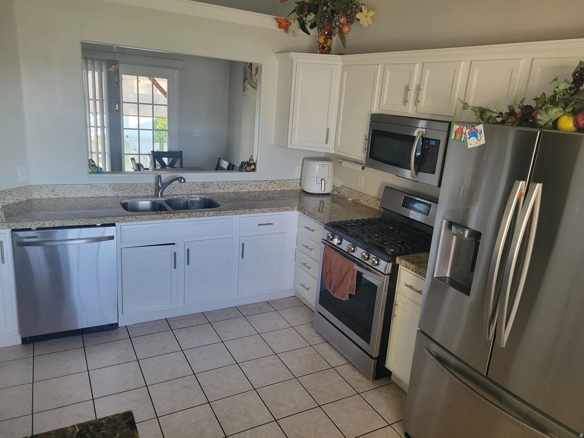 Galley-style kitchen featuring stainless steel appliances, including a gas range, microwave, and side-by-side refrigerator