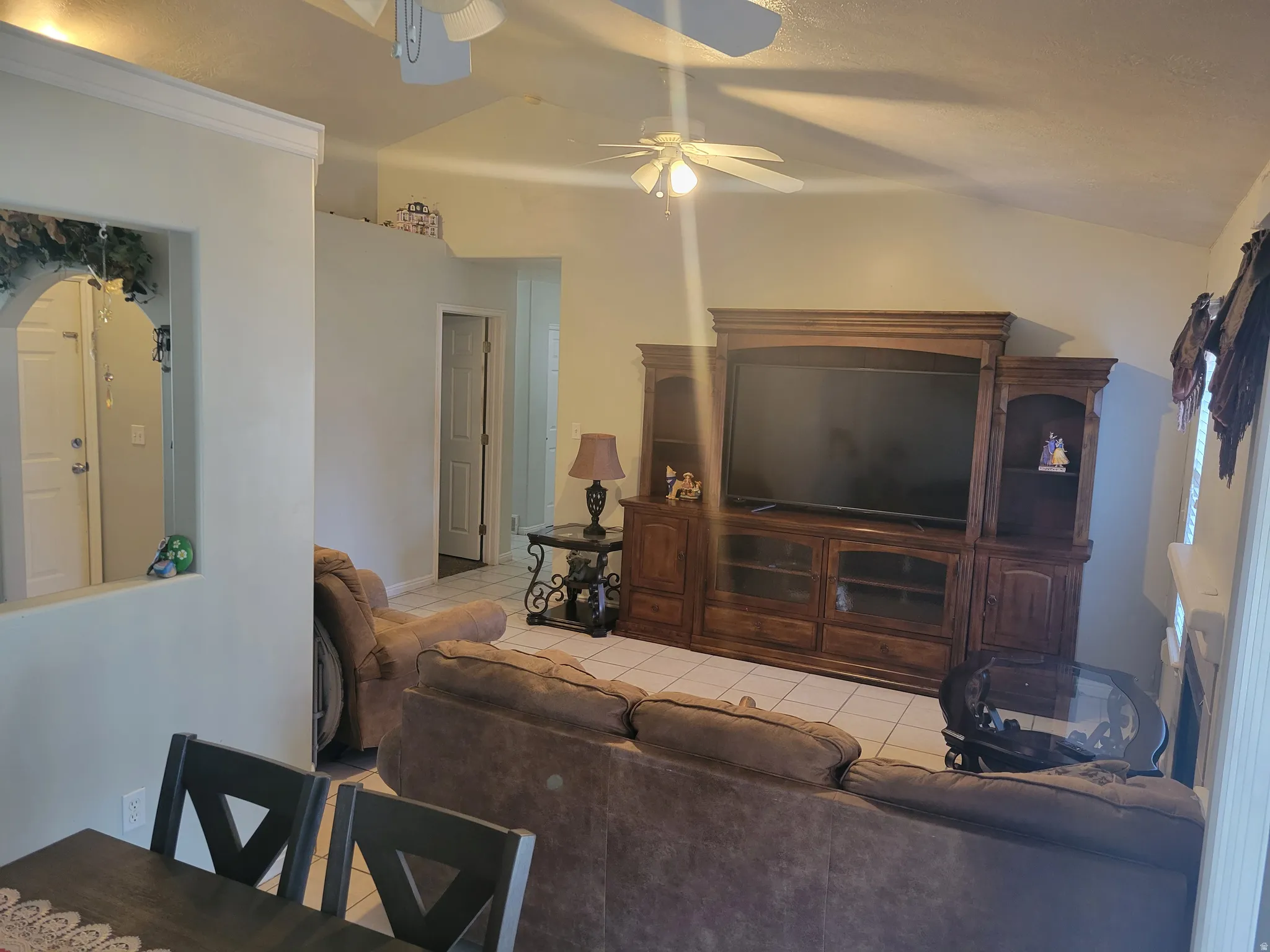 Spacious living area showcasing a wood-finish entertainment center with integrated cabinetry, recessed lighting, and ceiling fan