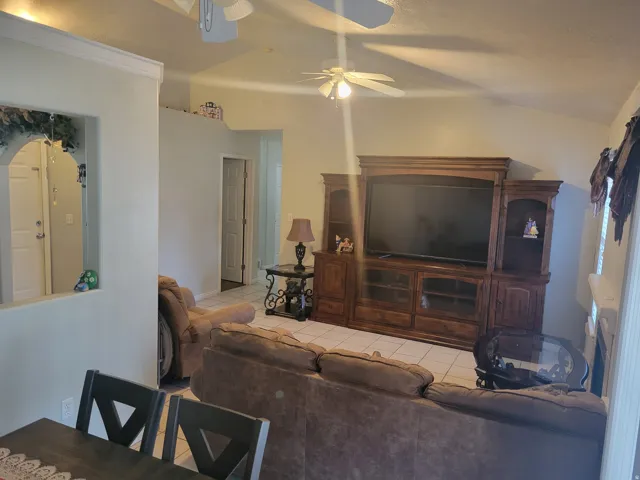 Spacious living area showcasing a wood-finish entertainment center with integrated cabinetry, recessed lighting, and ceiling fan