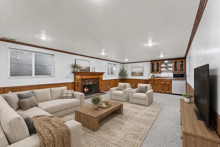 Spacious lower-level living area featuring a traditional wood and brick fireplace