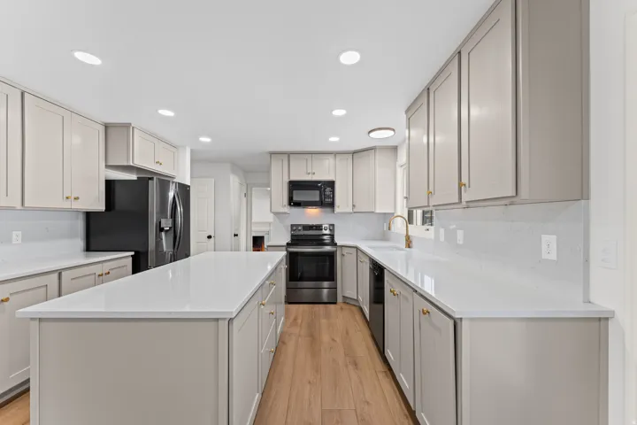 Chef's kitchen featuring white cabinetry with brushed gold hardware, white subway tile backsplash, and white quartz countertops