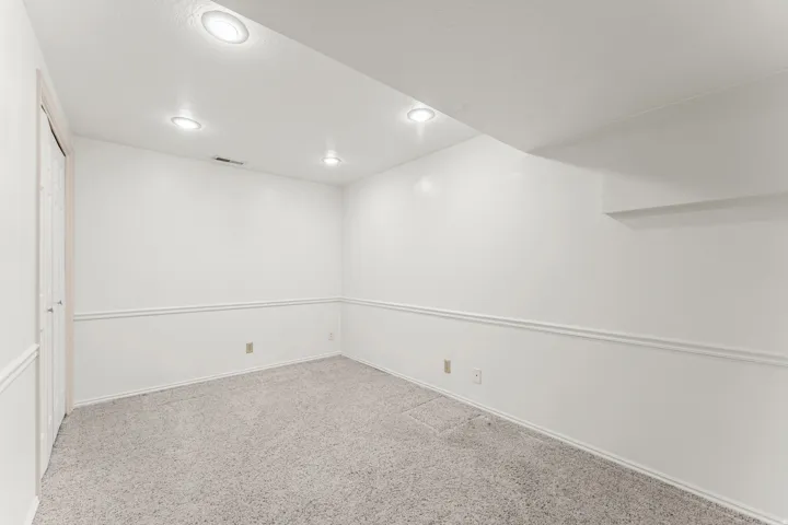 Bright interior space featuring light-colored carpeting, white walls with chair rail molding, and recessed lighting
