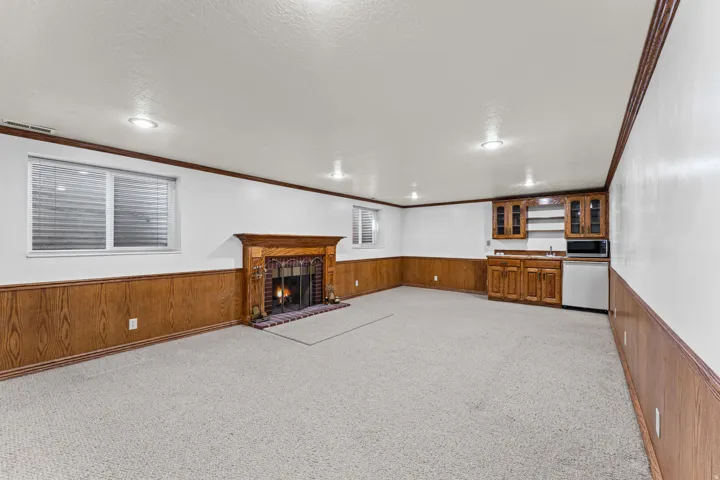 Spacious recreational room featuring wood-finish wainscoting, recessed ceiling lighting, and carpet flooring