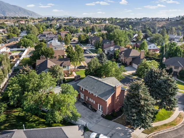 Red brick multi-story residence with a gray shingle roof, featuring multiple chimneys and a paved driveway