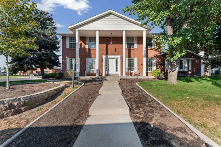 Classic brick Colonial with commanding front elevation featuring a white-columned portico, gabled roofline, and symmetrical facade
