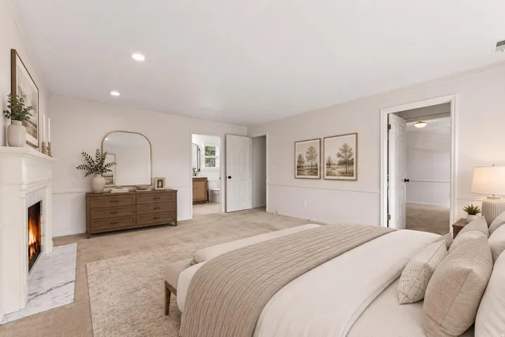 Spacious bedroom featuring a white mantel fireplace with a marble hearth, recessed lighting, crown molding, chair rail molding, and carpeted flooring