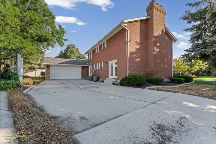 Brick exterior with a prominent brick chimney, an attached two-car garage, and a concrete driveway