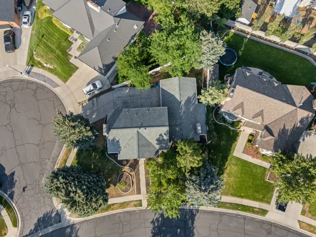 Aerial view showcasing a substantial residential property with slate-colored asphalt shingle roofing, situated on a tree-lined lot with mature landscaping