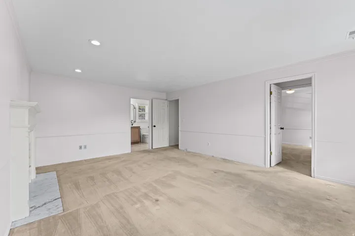 Spacious primary living area featuring pristine wood-finish flooring, recessed ceiling lighting, and multiple entry points