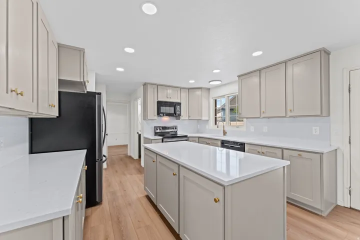 Modern kitchen featuring custom cabinetry in soft gray tones with brass hardware accents, white quartz countertops, and a spacious center island
