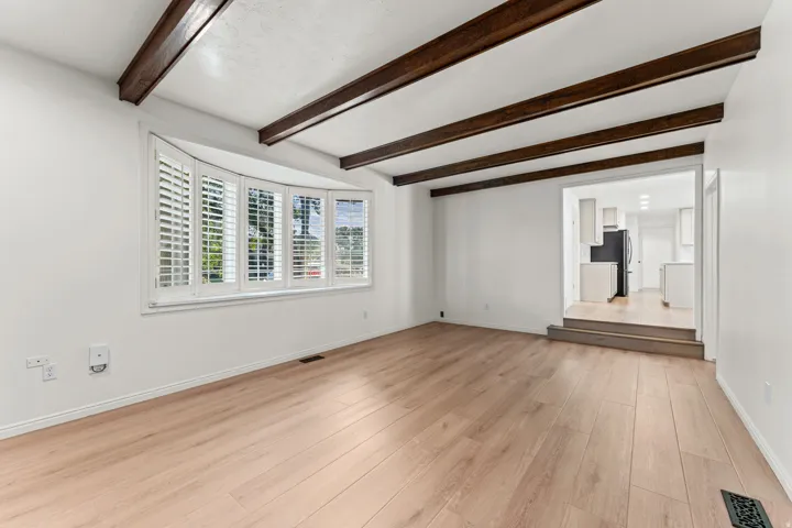 Spacious room with exposed wooden beam ceiling details and white walls