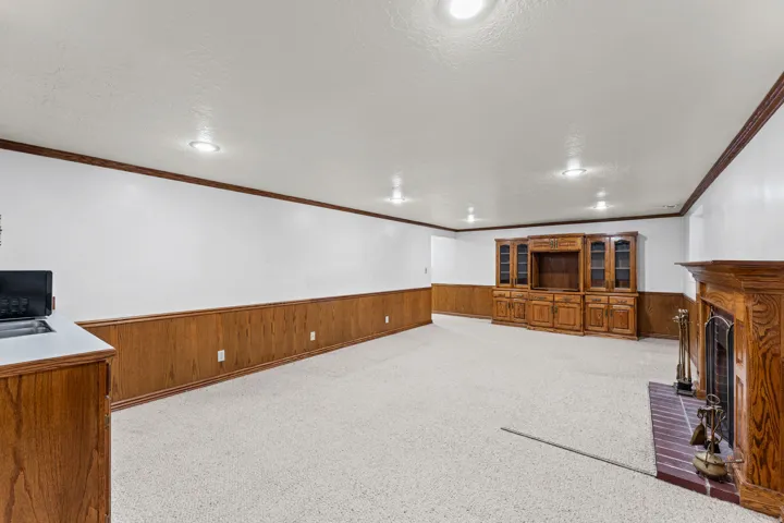 Spacious basement recreation room featuring wood-finish wainscoting, recessed ceiling lighting, and abundant open floor space