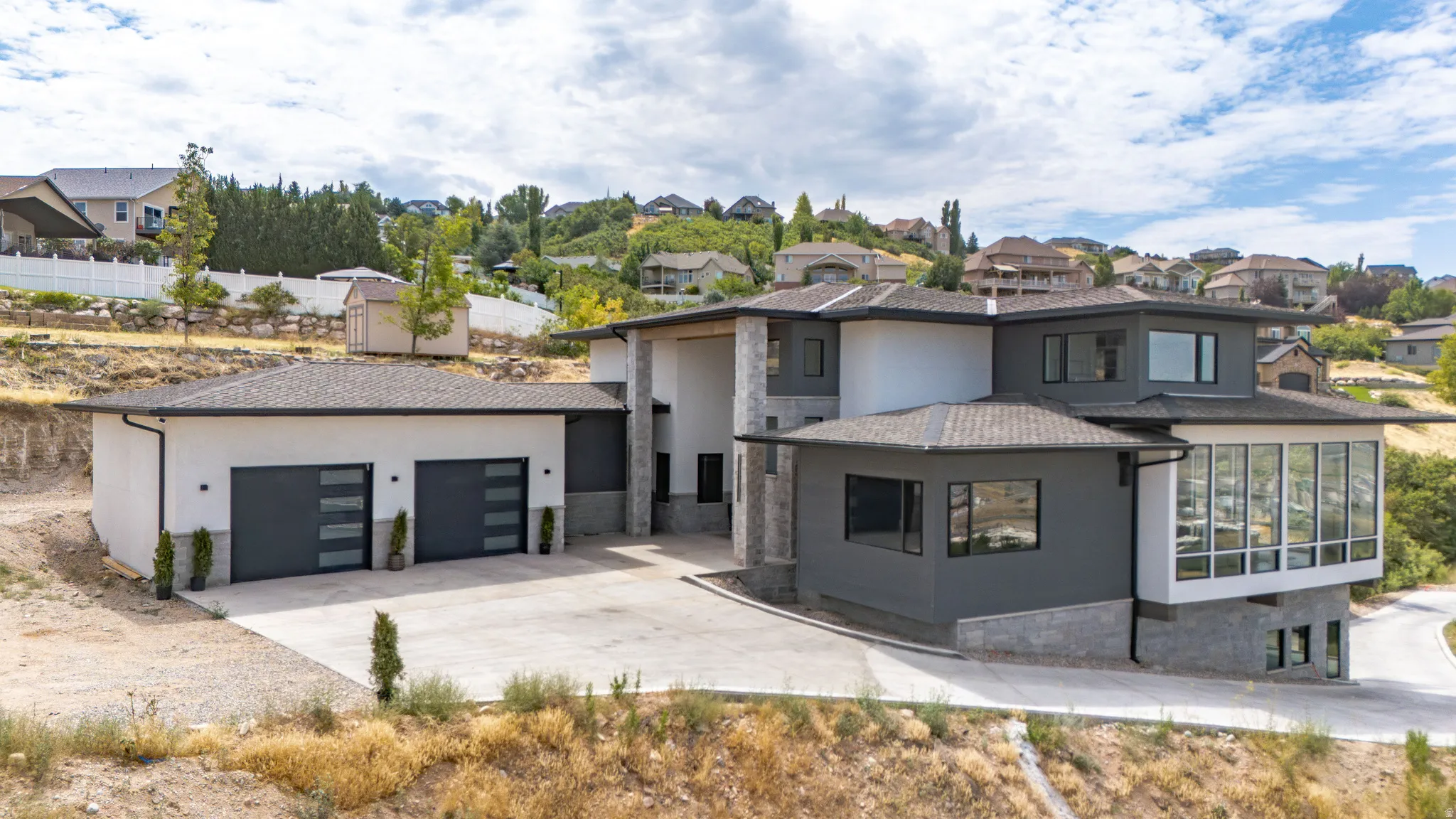 Modern multi-level exterior featuring a combination of white stucco, dark gray siding, and stone accents
