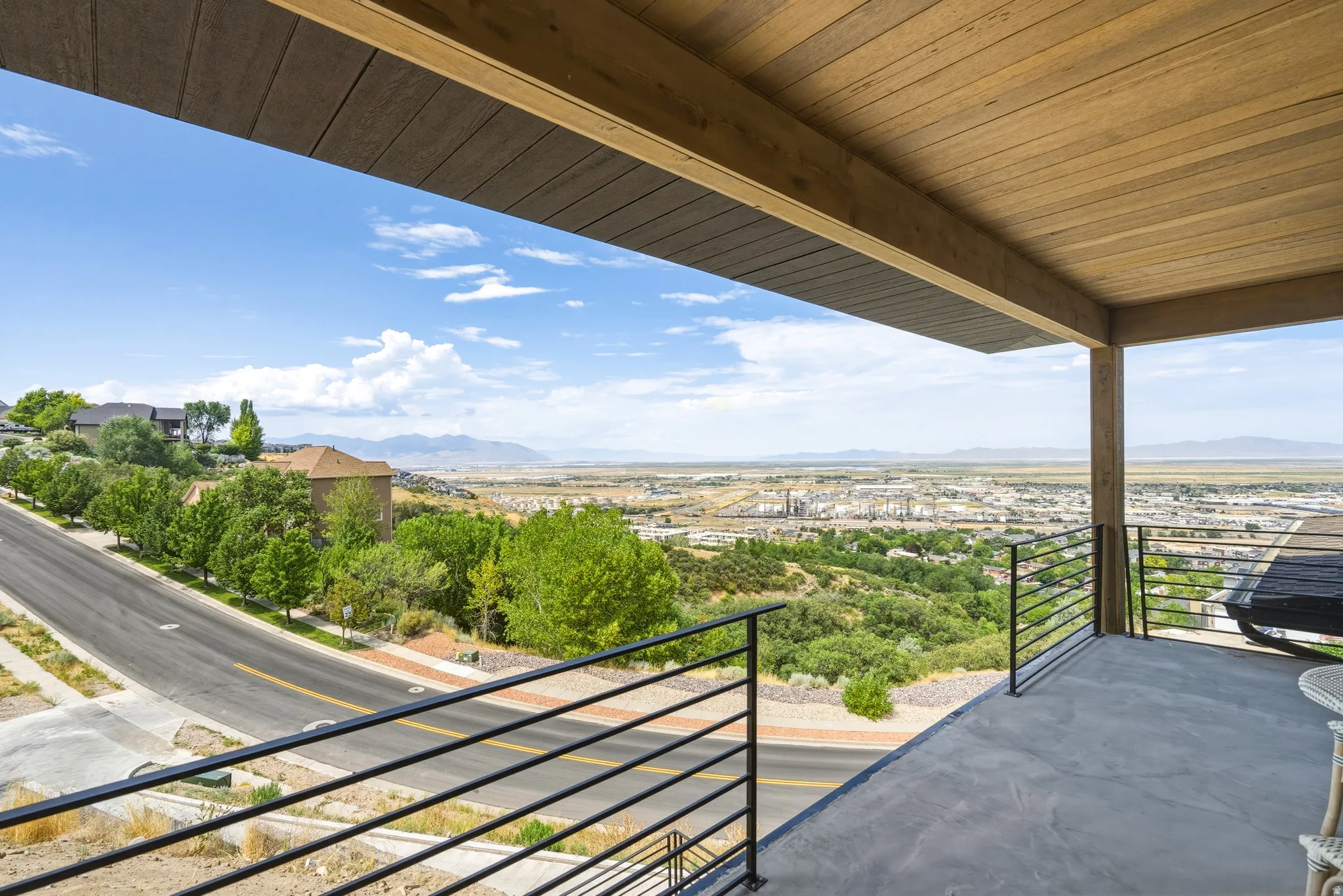Expansive outdoor patio with a planked wood-finish ceiling, sturdy support column, and contemporary horizontal bar railing