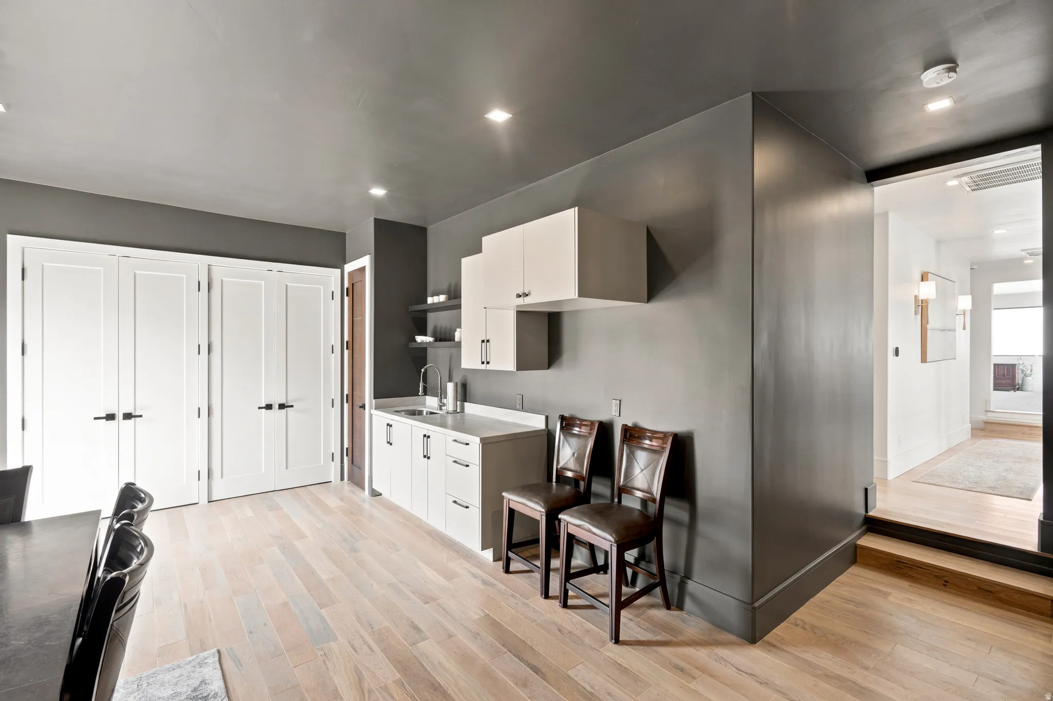Kitchenette featuring white cabinetry, a sink with a stainless steel faucet, and open shelving