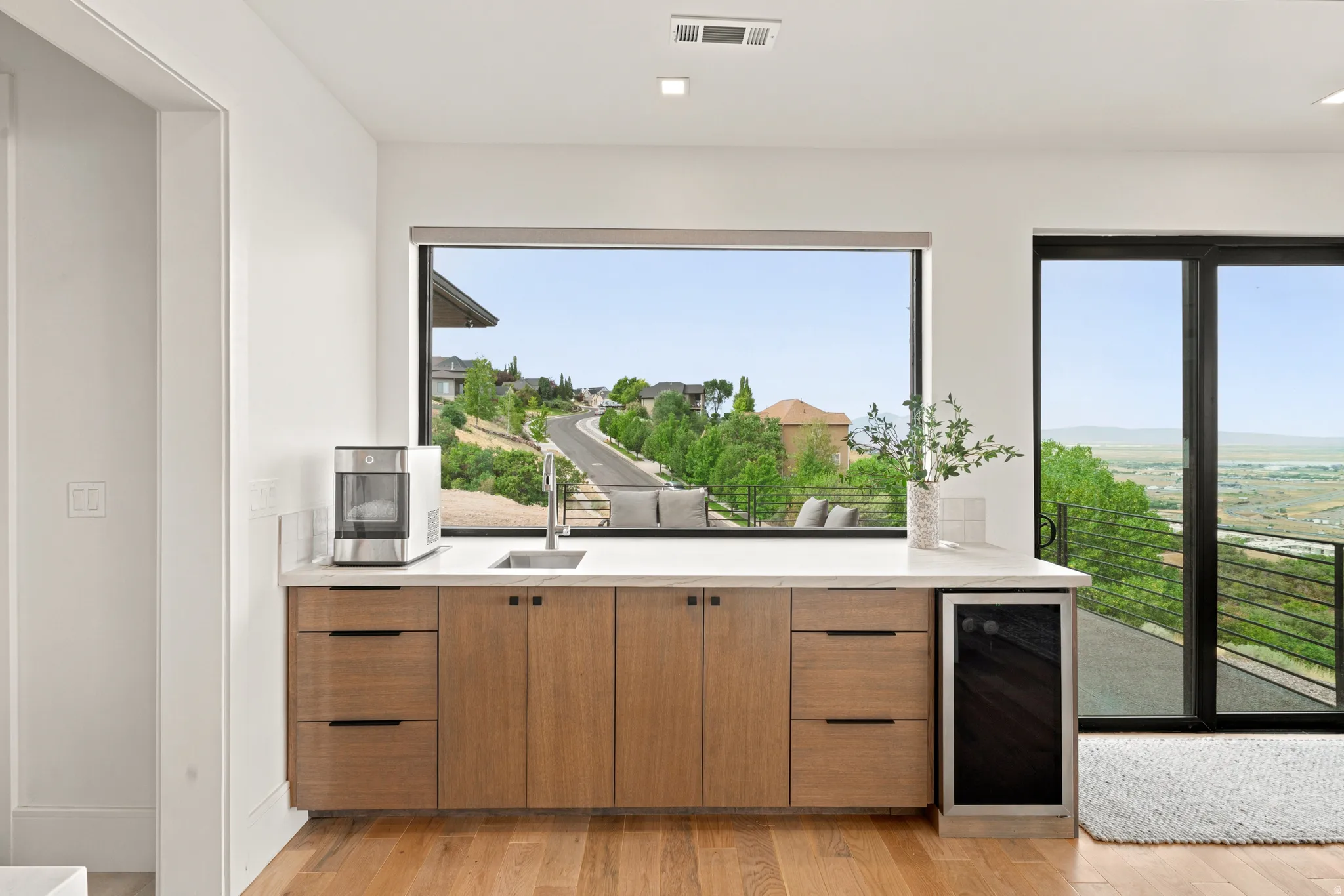 Built-in wet bar featuring wood-finish cabinetry, a light-toned countertop, and integrated sink