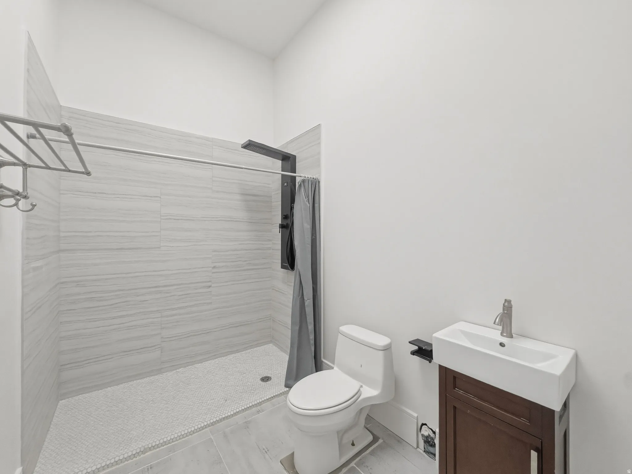 Modern bathroom featuring a walk-in shower with light-toned rectangular tile surround and a mosaic tile floor