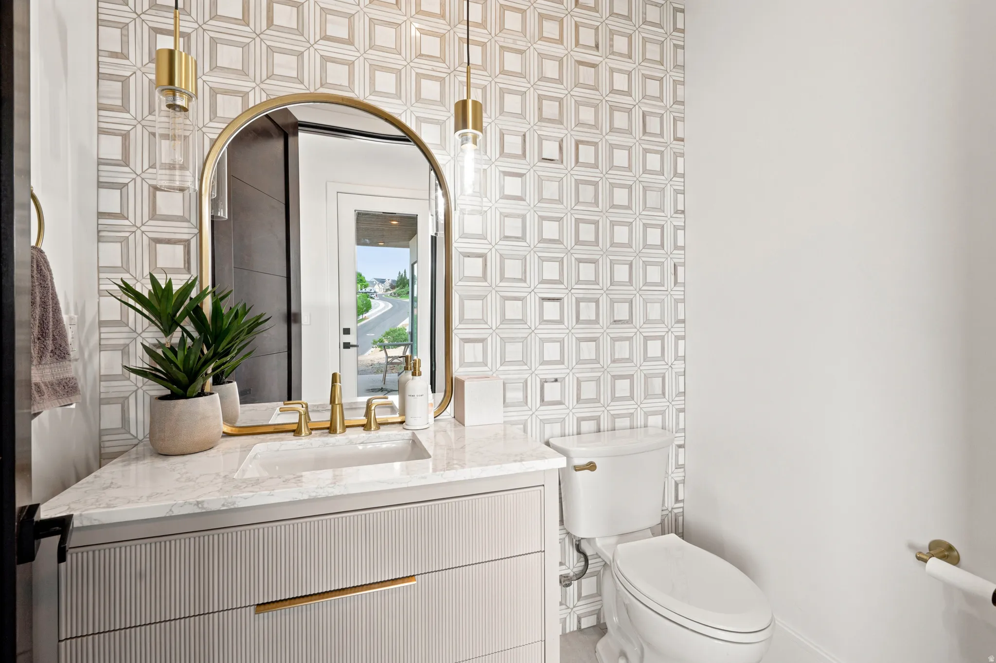 Bathroom vanity featuring a rectangular sink, gold-toned faucet, and a large arched mirror
