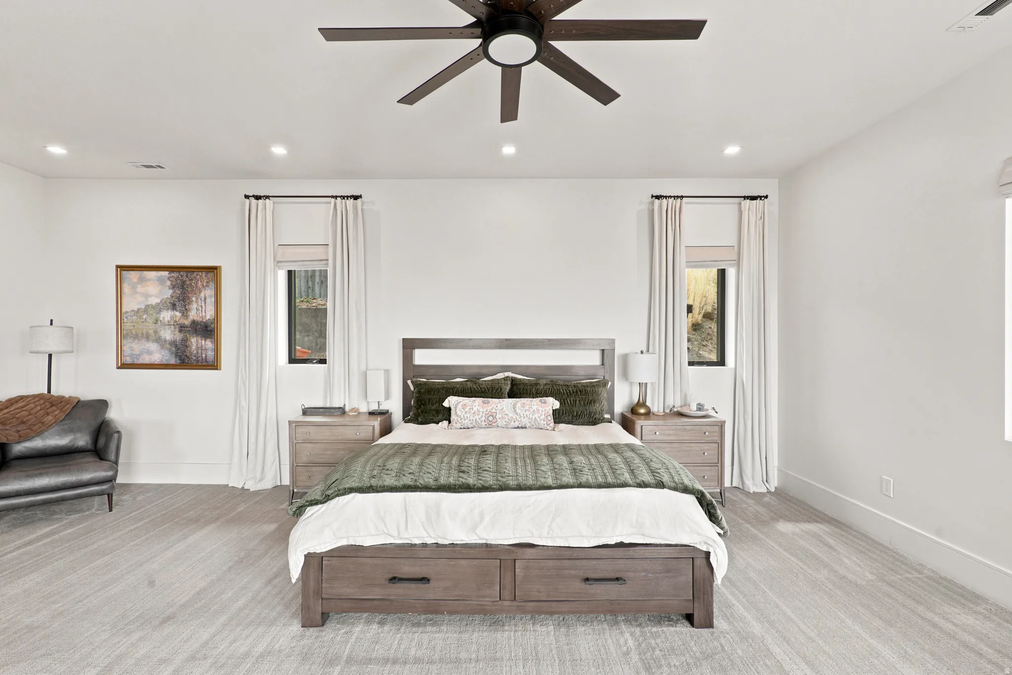 Spacious bedroom featuring light-toned flooring, recessed lighting, and a dark wood-finish ceiling fan