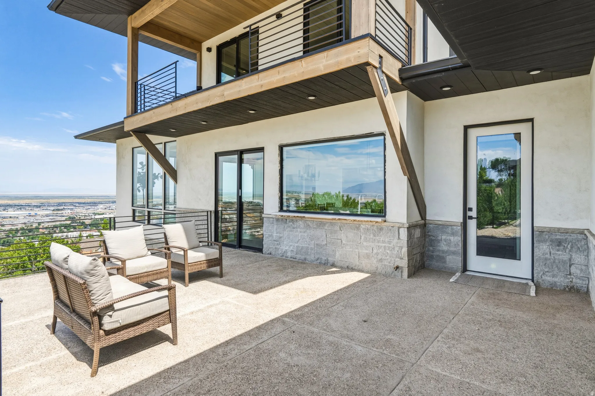 Expansive concrete patio area with a stone base, large windows, and a glass-paneled exterior door