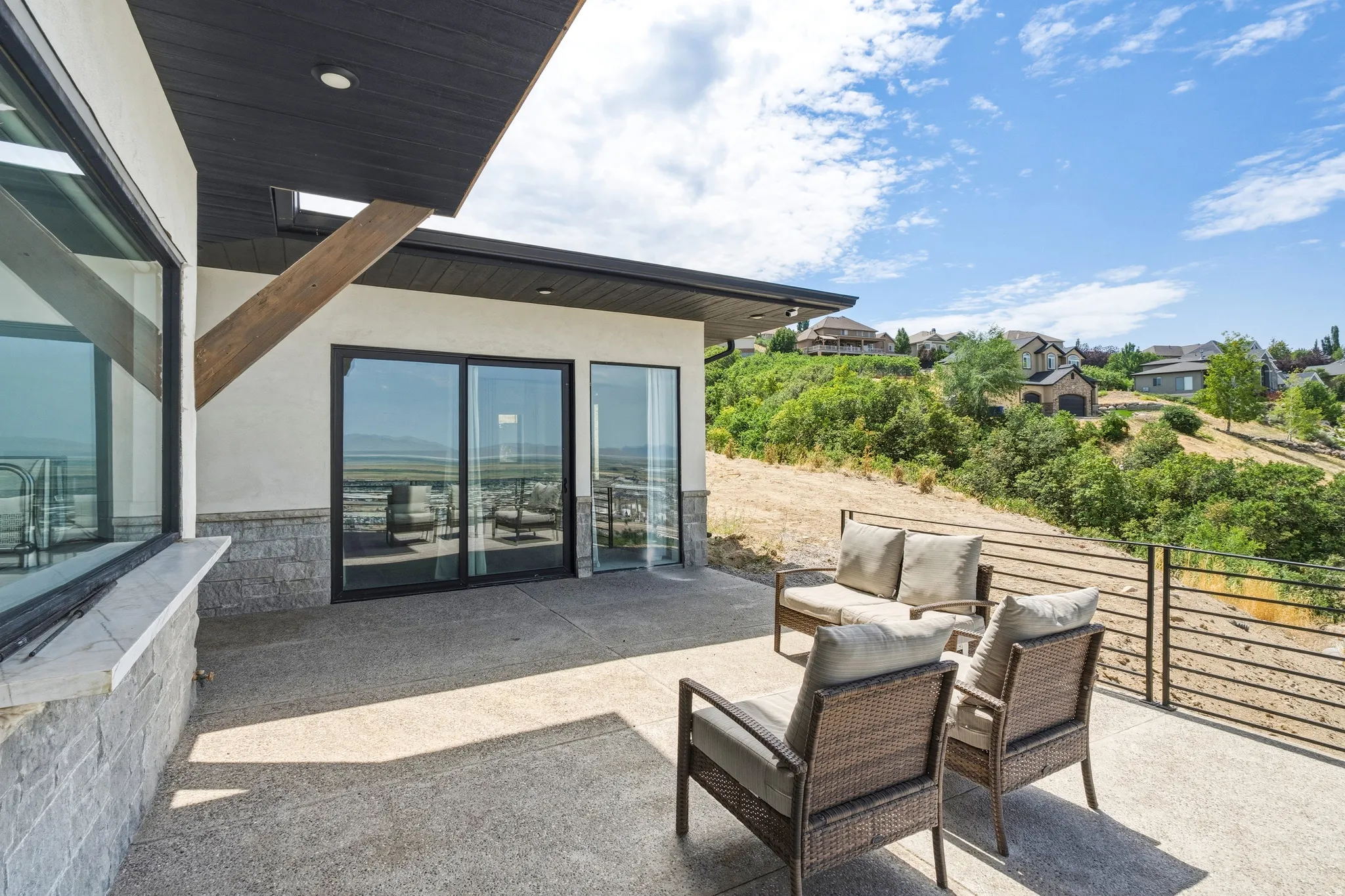 Expansive outdoor patio featuring a concrete surface and black horizontal railing