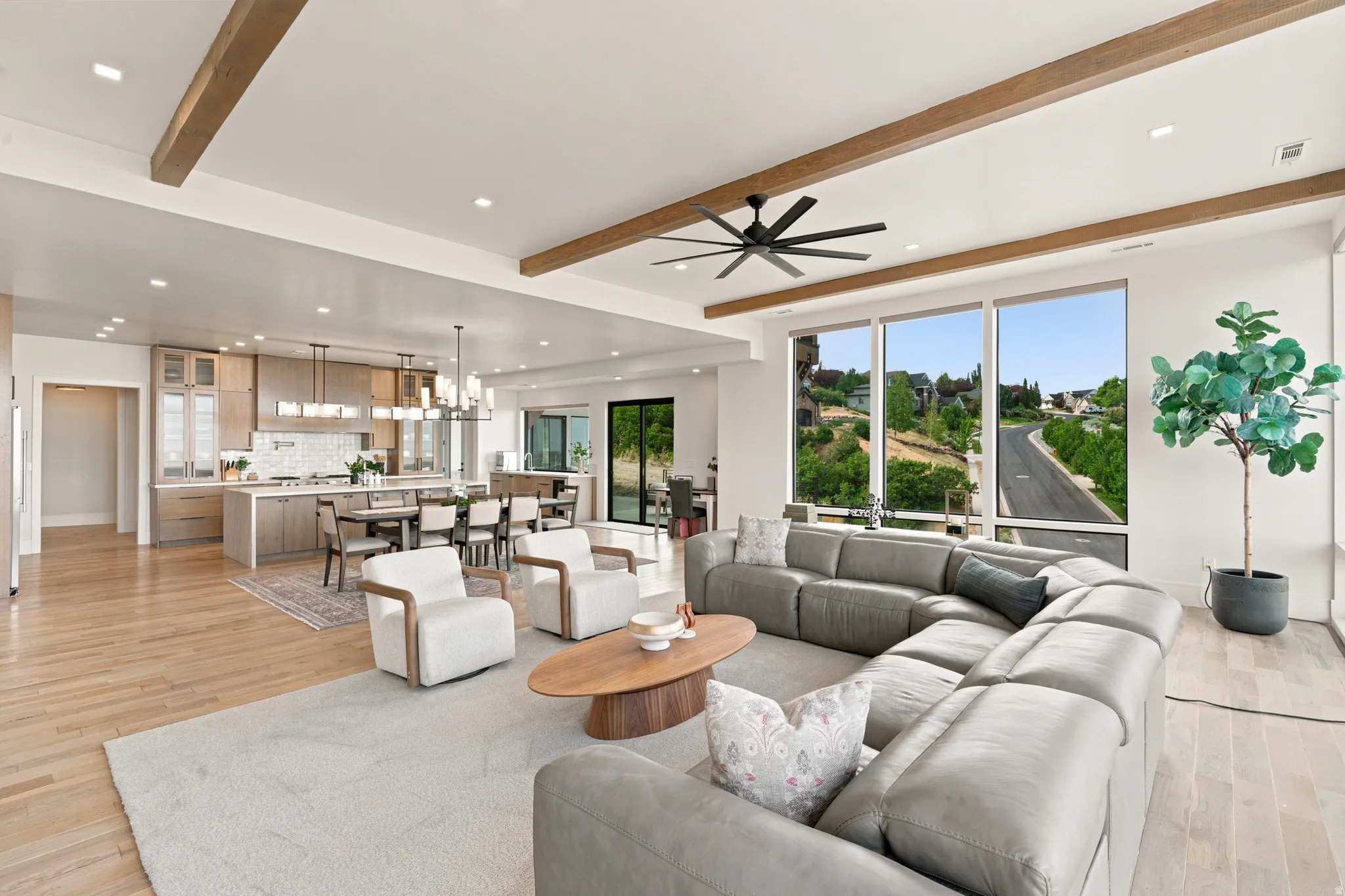 Open-concept living space featuring exposed wood beams, recessed lighting, and wood-finish flooring
