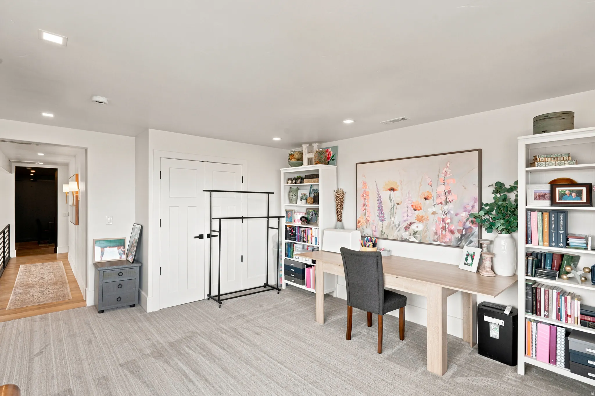 Spacious room featuring light-toned wood-finish flooring, recessed lighting, and white bi-fold closet doors
