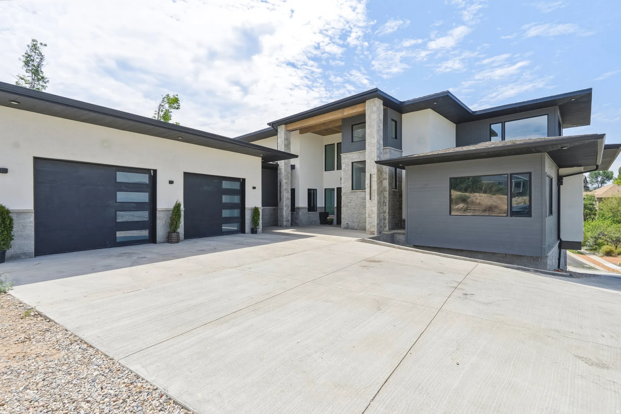 Contemporary residence featuring a multi-level design, a concrete driveway, and a two-car garage with frosted glass paneling