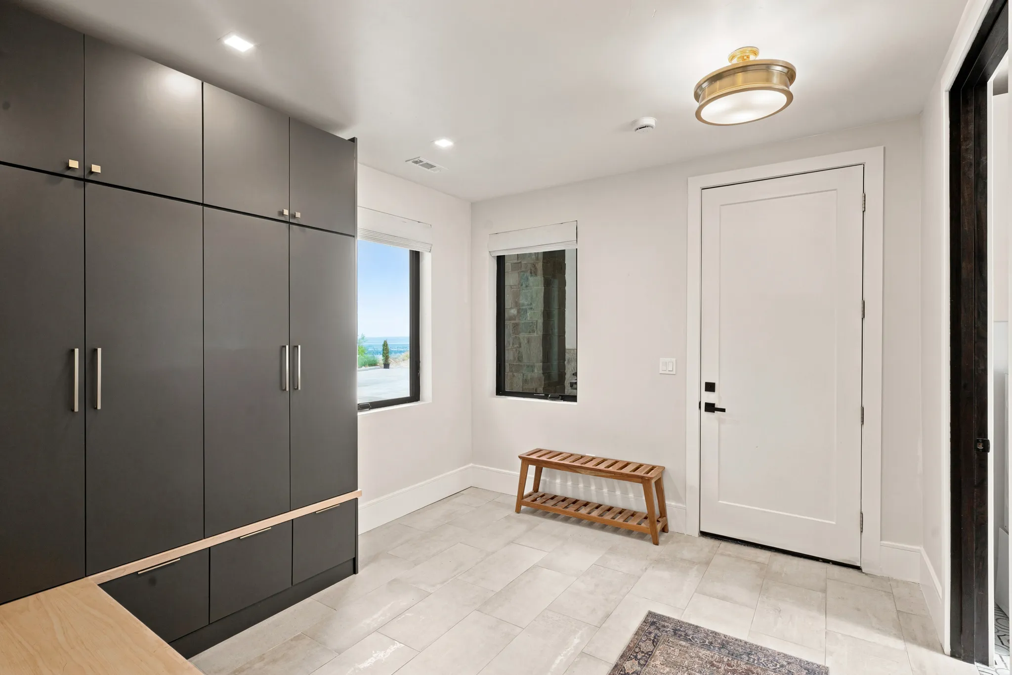 Entryway featuring full-height dark cabinetry with integrated pulls, light-toned tile flooring, recessed lighting, and a contemporary flush-mount ceiling fixture