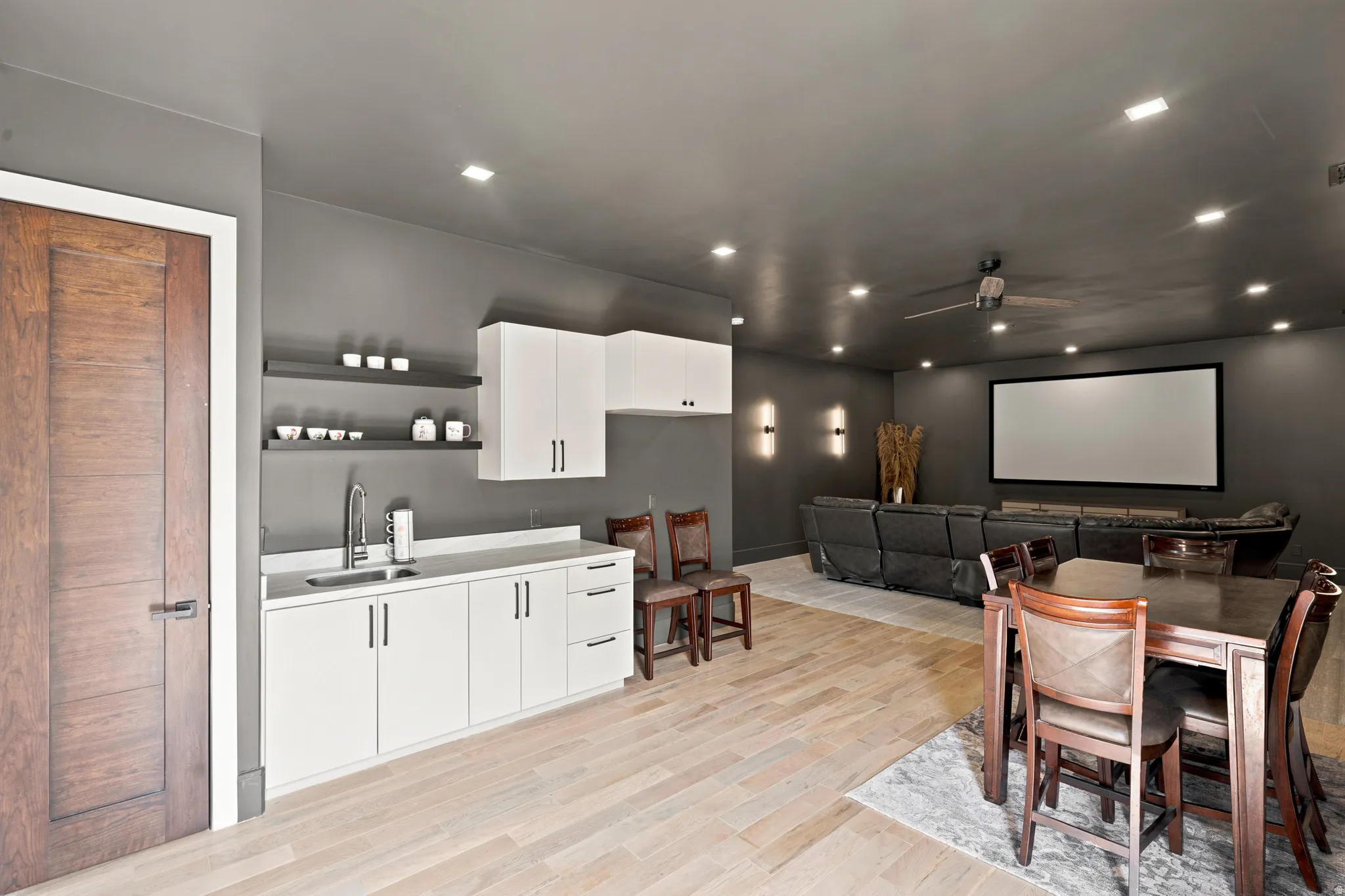 Entertainment room featuring a wet bar with white cabinetry, light countertops, and an undermount sink