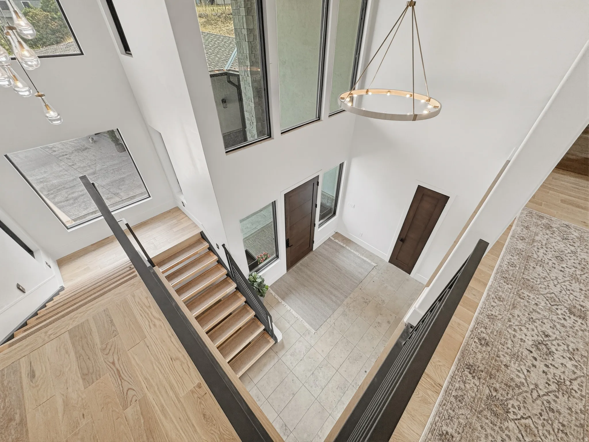 Grand entryway featuring a two-story ceiling, light wood-finish flooring, and a contemporary chandelier