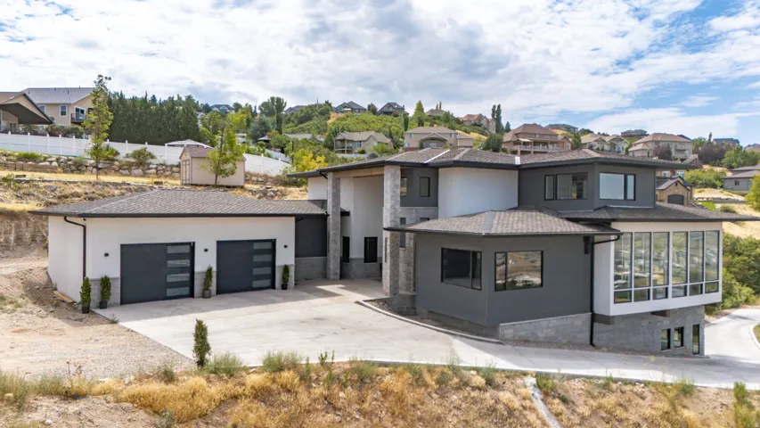 Modern multi-level exterior featuring a combination of white stucco, dark gray siding, and stone accents