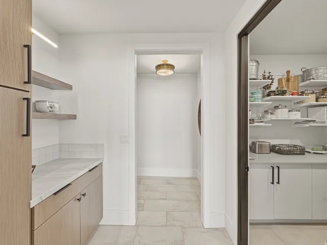 Kitchen pantry with light wood-finish cabinetry, white countertop, and white subway tile backsplash