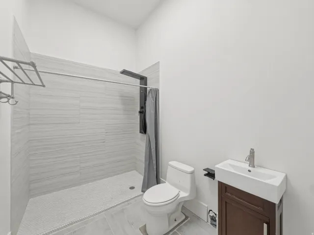 Modern bathroom featuring a walk-in shower with light-toned rectangular tile surround and a mosaic tile floor
