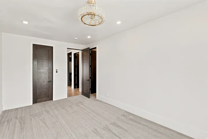 Bright room featuring a crystal chandelier, recessed lighting, light-toned carpeting, and dark wood-finish interior doors