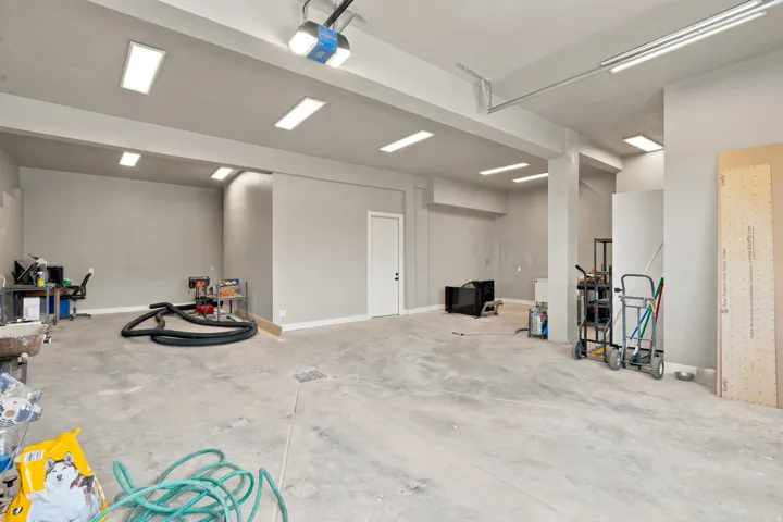 Spacious garage featuring a concrete floor, abundant overhead fluorescent lighting, and a garage door opener