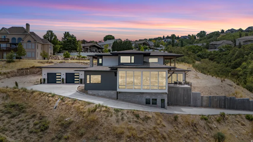Contemporary architectural design featuring large windows, a multi-level structure, a two-car garage, and extensive retaining walls