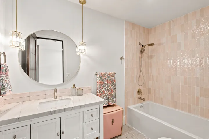 Bathroom featuring a white vanity with a marble-finish countertop, undermount sink, and brass-tone faucet
